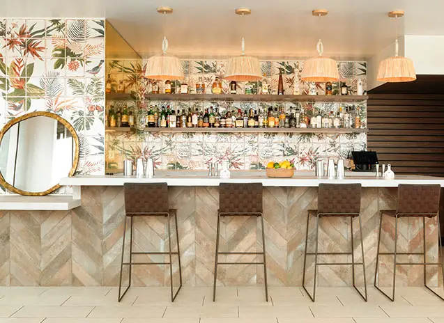 Stylish bar with modern and sleek decor. It is adorned with a floral and tropical wall background, adding a vibrant and fresh touch to the ambiance.